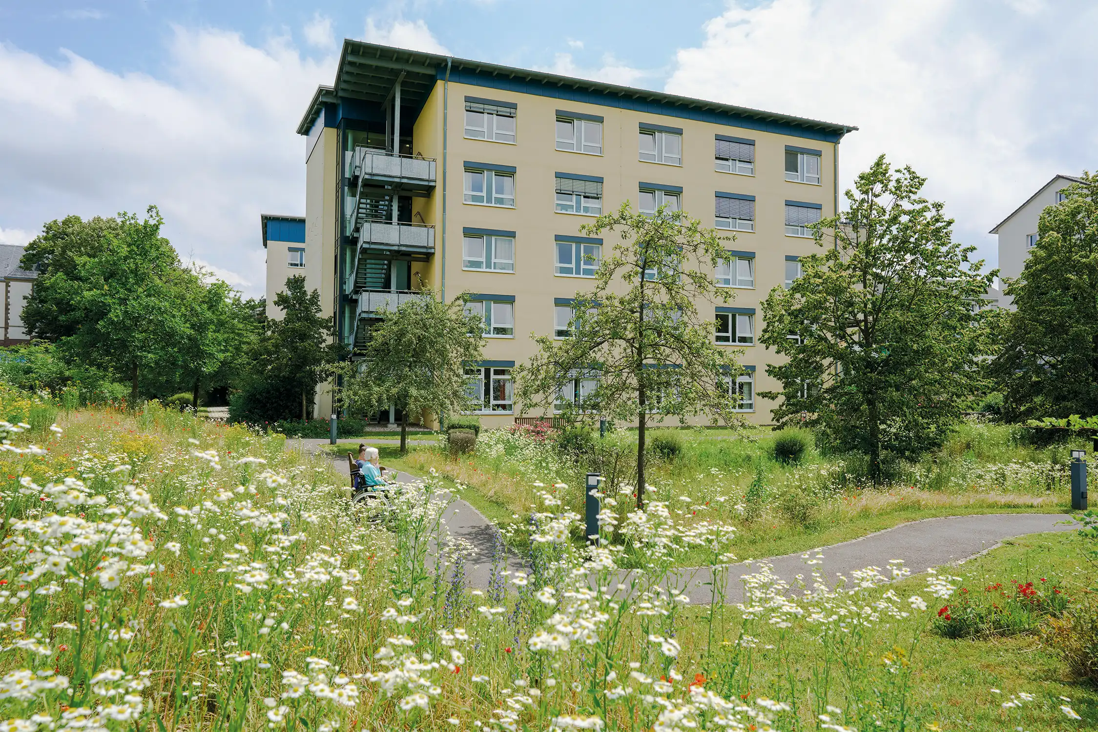 Quelle: BLV Zwei Frauen sitzen auf einer Bank hinter dem Haus Karlsruher Weg.