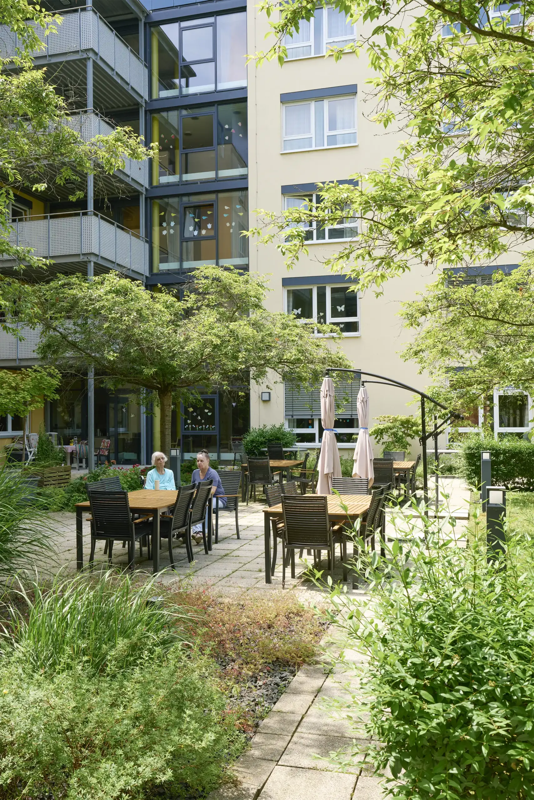 Quelle: BLV Zwei Frauen sitzen an einem Tisch im Garten des Hauses Karlsruher Weg.