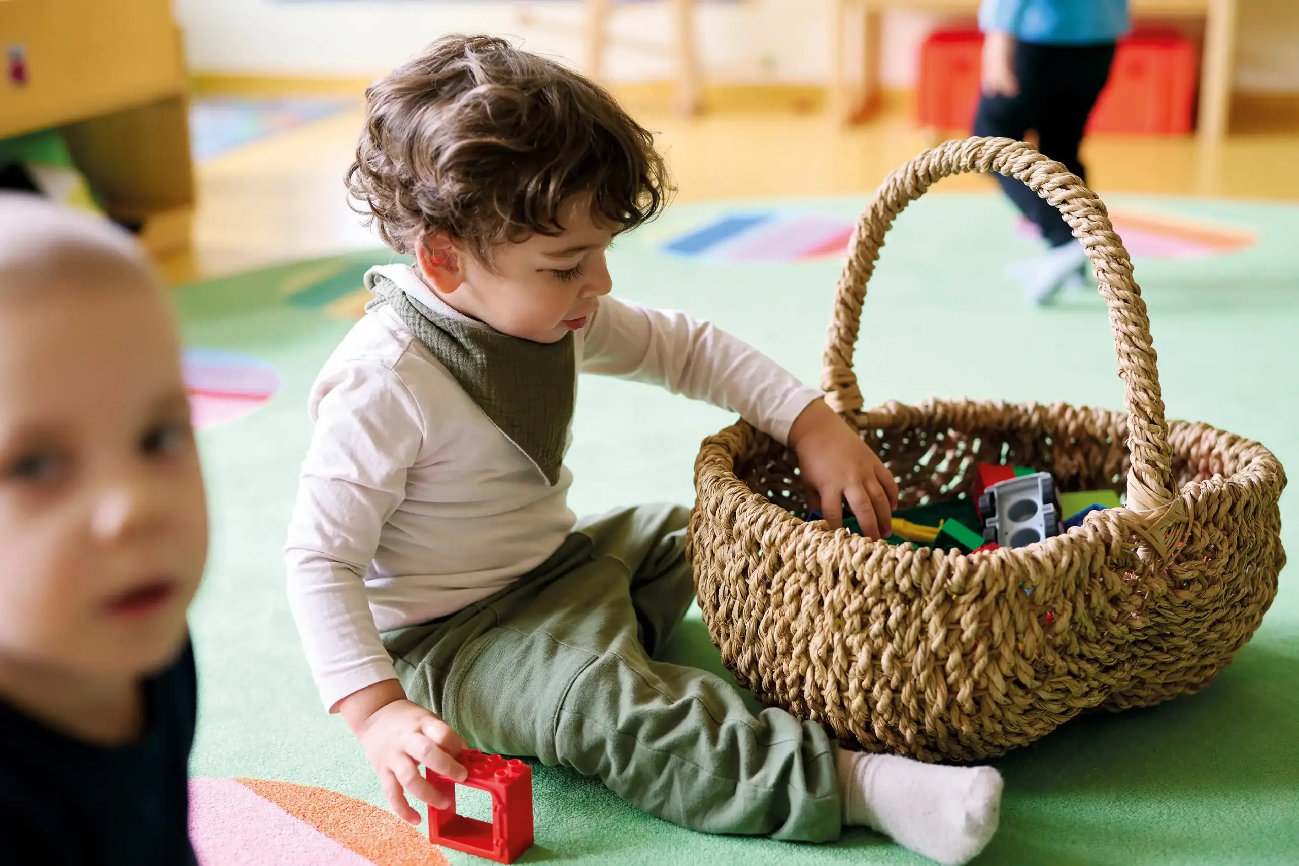 Quelle: BLV Ein Kind sitzt auf dem Boden und wühlt in einem Korb voller Duplo-Steine.