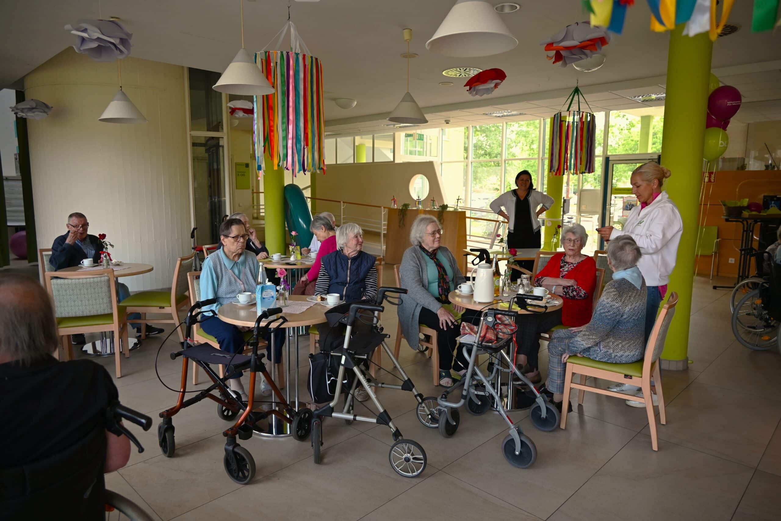 Die Bewohnerinnen und Bewohner des Altenhilfezentrum Karlsruhe-Nordost sitzen gemütlich im Foyer der Einrichtung beisammen.