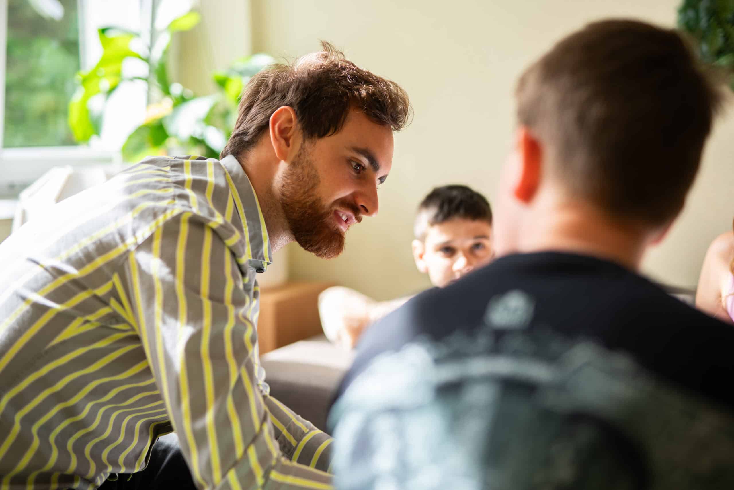 Ein junger Mann im Gespräch mit zwei Jungen.