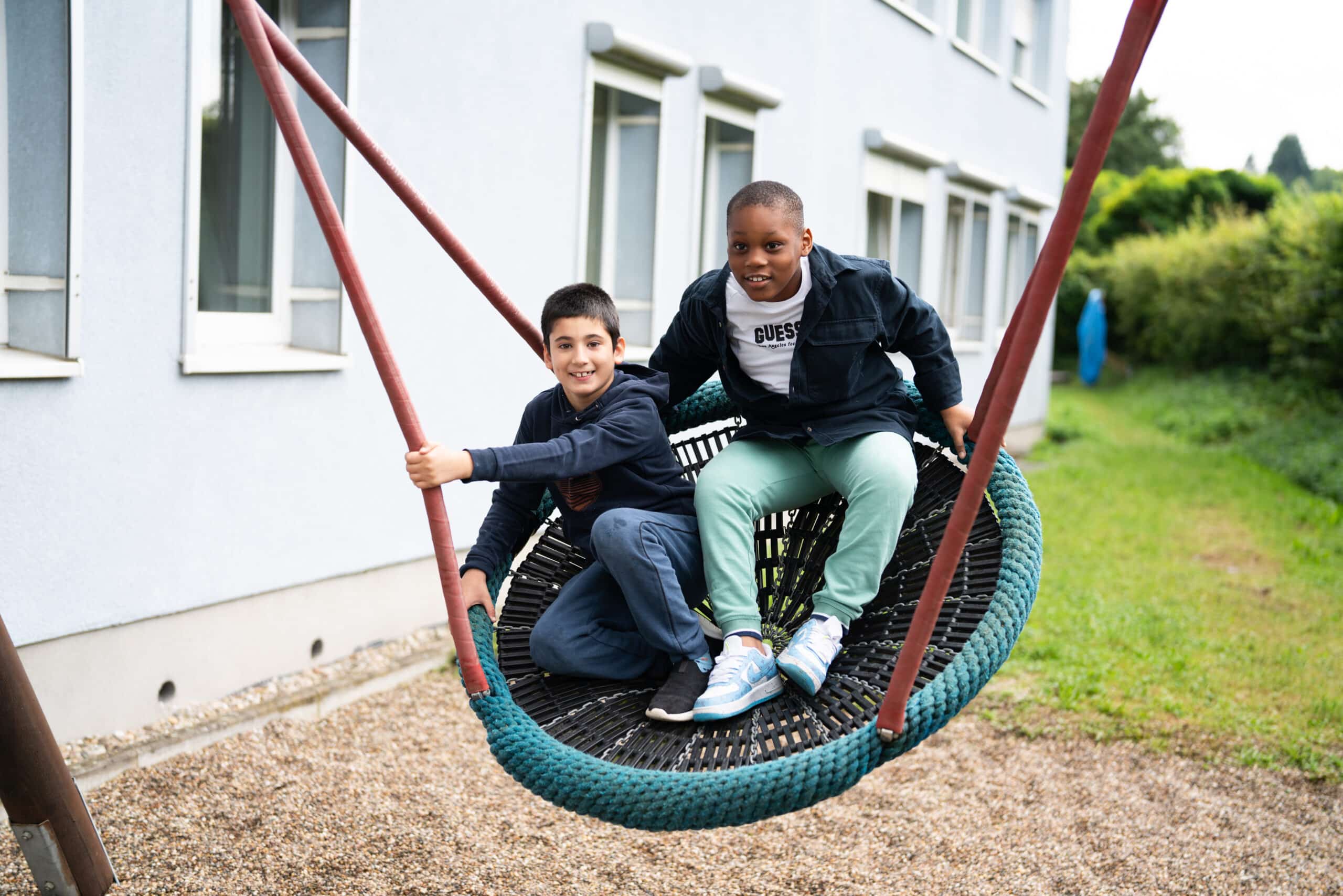 Zwei Kinder sitzen in einer großen Schaukel und schaukeln.