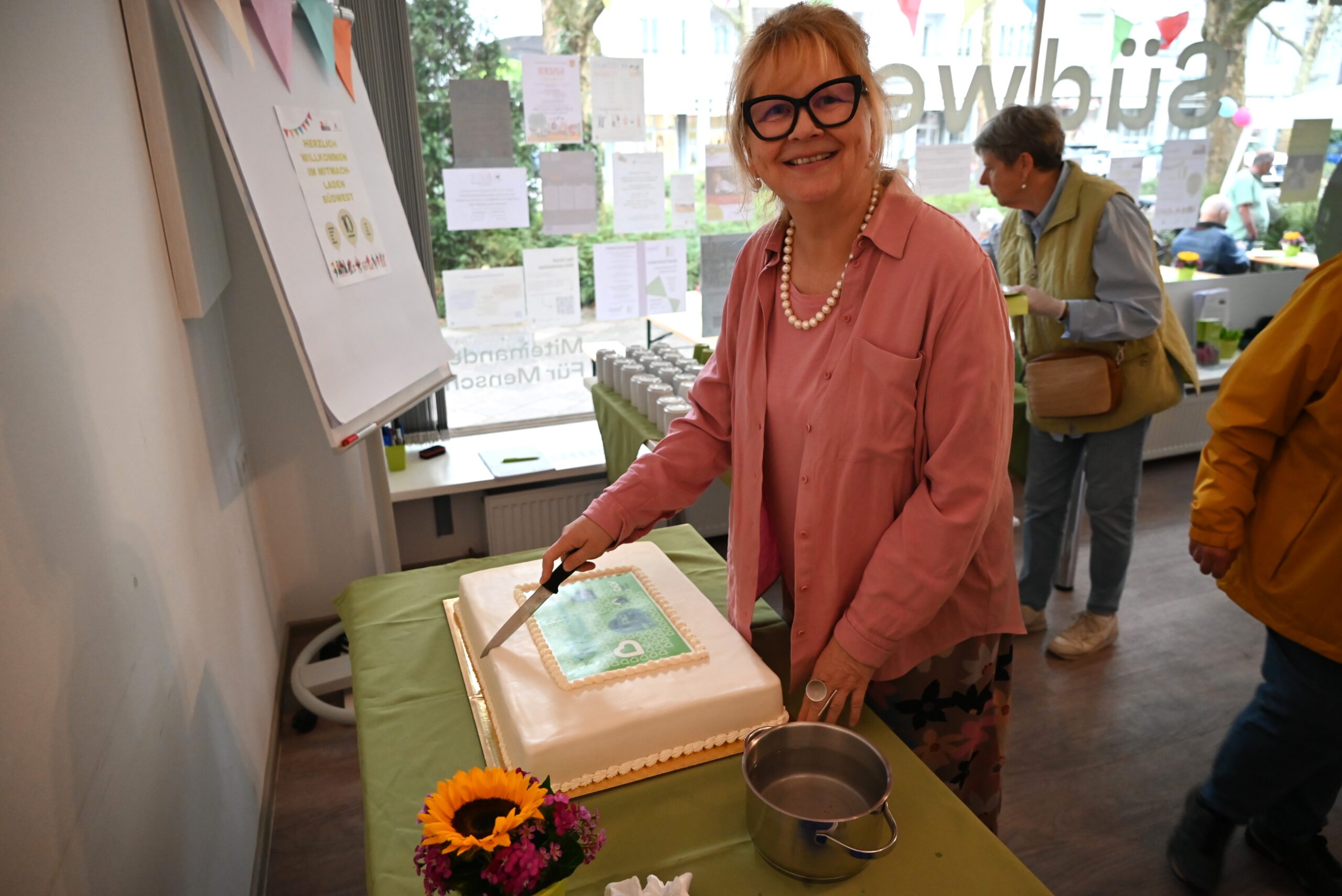 BLV Vorstand Christine Jung-Weyand schneidet die Geburtstagstorte des Mitmach-Ladens an.